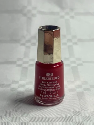Mavala Versatile Red nagellack - Nagellack från Mavala i färgen Versatile Red 986. Intensivt röd nyans med krämig finish och lång hållbarhet. Kommer i en liten glasflaska på 5 ml med guldfärgat lock. Formulan är 11 FREE och ger superlång glans.