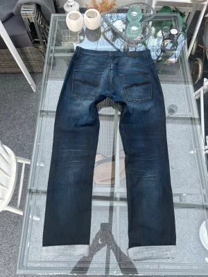 Nudie Jeans Thin Finn W34/L34 Dark Wash - Säljer ett par Nudie Thin Finn i mörk tvätt. Slim/tapered fit med snygg naturlig fading och riktigt fin passform. Storlek W34 L34. Stretchdenim (98% bomull, 2% elastan) som sitter bekvämt. Bra skick utan större slitage. Klassisk premium denim som passar till allt.  Perfekta om du gillar vintage denim, minimalistisk stil eller clean streetwear fits. Nypris betydligt högre.