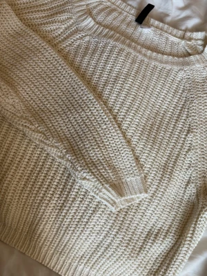 Vit grovstickad tröja - Säljer en vit grovstickad tröja med rund hals och långa ärmar. Tröjan har ett chunky stickat mönster och ribbade muddar vid ärmslut och nederkant. Perfekt för lager-på-lager och en avslappnad stil.