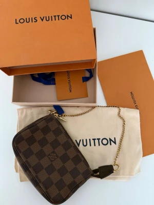 Louis Vuitton Mini Pochette Accessoires – Damier Ebene - Säljer min Louis Vuitton Mini Pochette Accessoires i Damier Ebene Canvas. Väskan är i perfekt skick, helt utan defekter, slitage eller fläckar. Använd mycket försiktigt.