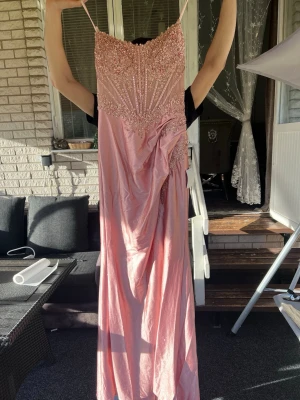 Rosa långklänning med paljettdetaljer - Elegant rosa långklänning med smala axelband och vacker paljettutsmyckning upptill. Klänningen har draperad detalj i midjan och glansigt tyg som ger en lyxig känsla. Perfekt för speciella tillfällen. Priset går att diskutera! 