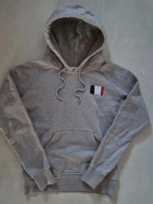 Grå hoodie från AMI Paris - Snygg unik  hoodie från AMI Paris med broderad logga i svart, vitt och rött på bröstet. Perfekt för dig som vill ha en unik men samtidigt snygg och lyxig Hoodie.                                                           Hör gärna av er vid frågor eller funderingar!    Mvh Melker