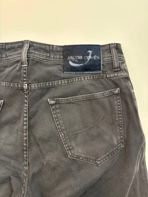 Svarta jeans från Jacob Cohen - Snygga svarta jeans från Jacob Cohen med klassisk femficksdesign och rak passform. Jeansen har en diskret logotyp-patch baktill i midjan och är tillverkade i ett mjukt bomullsmaterial med stretch för extra komfort.