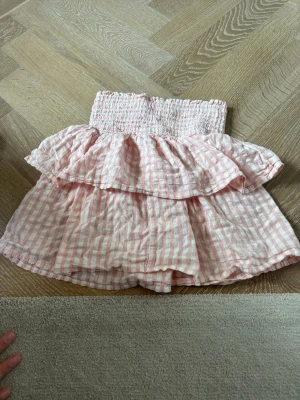 Rosa och vit rutig volangkjol - Söt kortkjol med rosa och vita rutor, smockad midja och dubbla volanger. Perfekt för dig som gillar en romantisk och lekfull stil. Kjolen är gjord i ett lätt bomullstyg som passar bra till varma dagar.Kjolen har ett lite hål vid sidan (bild 3) men det märks inte av. Skriv för fler blider. Pris går att diskutera!🥰