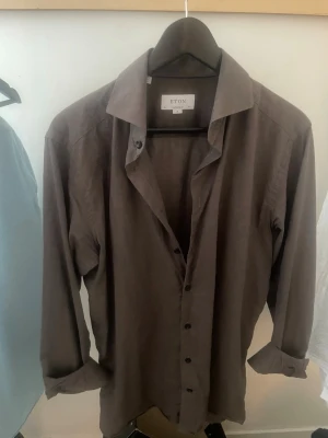 Brun tunn skjorta från Eton - Snygg brun skjorta från Eton i linnemix med modern passform. Skjortan har klassisk krage, långa ärmar och knäppning framtill. Perfekt för en stilren och avslappnad look. Passar mer som L trots att den säger M