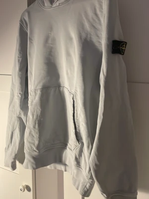 Ljusgrön hoodie från Stone Island - Snygg ljusgrön hoodie från Stone Island Junior med klassisk huva och känguruficka framtill. Ikonisk svart logopatch på ärmen. Tillverkad i mjukt bomullsmaterial som känns skönt mot huden. Perfekt för dig som gillar streetwear och vill ha en clean look. Tröjan är i storlek 14/170, kan tänka mig gå ner i pris vid snabb försäljning 