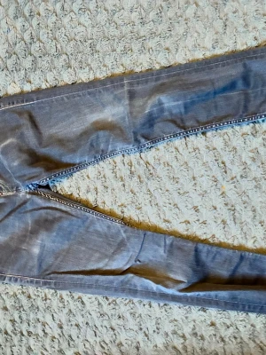 Blå slim fit jeans med slitningar från Levis  - Snygga blå slim fit jeans med lätt slitna detaljer och klassiska bakfickor. Jeansen har smal passform och är tillverkade i denim med stretch för extra komfort. Perfekta för en avslappnad och trendig look.