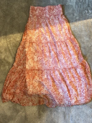Långkjol från Gina Tricot - Säljer en långkjol från Gina Tricot med rosa mönster på. Kjolen har smock i midjan för skön passform och är gjord i ett lätt och luftigt material. Storlek 146/152
