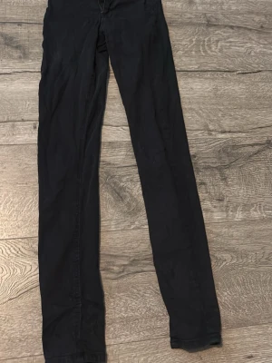 Svarta Molly jeans från Gina Tricot - Säljer ett par svarta Molly jeans från Gina Tricot i storlek XS. Jeansen har hög midja, smal passform och klassisk femficksdesign. Tillverkade i stretchigt material för extra komfort. Perfekta till alla dina outfits!
