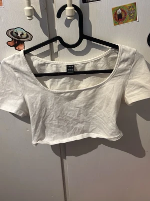 Vit croppad topp från SHEIN - En basic vit croppad topp från SHEIN med korta ärmar och rund halsringning. Tillverkad i mjuk bomull, perfekt att styla med jeans eller kjol. Enkel och fräsch design som passar till många olika looks.