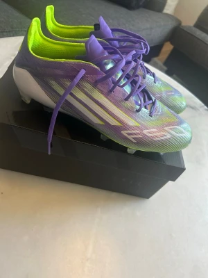 Adidas F50 elite  - Säljer ett par Adidas X Speedflow fotbollsskor i en riktigt fet färgkombo av lila, neon-gult och vitt. Skorna har snörning, låg profil och mönstrad ovandel i syntetmaterial för maxad bollkontroll. Perfekta för dig som vill sticka ut på planen!