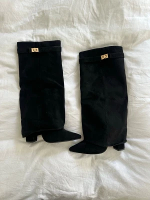 Svarta mockastövlar💓 - Snygga svarta knähöga stövlar i mocka med spetsig tå och guldfärgade detaljer upptill. Stövlarna har en klassisk och stilren design som passar perfekt till höst- och vinterlooken. Dessa är helt oanvända då jag skulle ha de på nyår men de levererades för sent. På sista bilden ser man hur en liten del av sömmen släppt på detaljen men gör ingen skillnad i helhetsuttrycket! Köpa från boohoo - nypris 1200kr💓