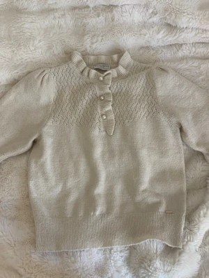 Stickad tröja - Söt stickad tröja med korta ärmar från Holly&Whyte i storlek S. Har mycket fina detaljer såsom knappar i kragen. Den har blivit något sliten i tyget men inget som man tänker på.
