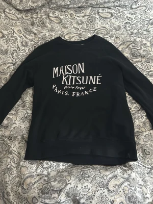 Maison kitsune sweatshirt - Säljer min as feta maison kitsune sweatshirt som är hel svart med vit text.  Tröjan har inga defekter eller något alls. Den är använd och texten är lite sliten men det märker man knappt. Pris går att diskutera!