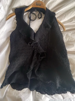 Nelly halterneck topp - Snygg svart halterneck topp med  volangdetaljer framtill. Toppen är från Nelly i stl xs super söt 