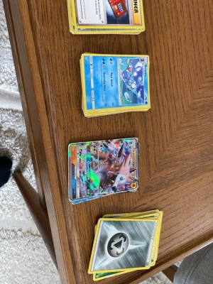 Pokémonkort Lycanroc GX och fler - Säljer ett gäng Pokémonkort, bland annat Lycanroc GX med holografisk yta och flera andra kort som energikort, Pokémons och tränarkort. Kortens design är färgstark med olika motiv och detaljer. Perfekt för dig som samlar eller spelar Pokémon TCG. Större delen av korten är från 2017 och 2016 men har förvarats i en låda( se sista bilden). Pris kan diskuteras 