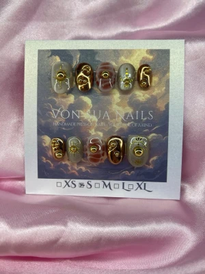 Relic (S);ExtraShortOval  - Unika Handgjorda press-on naglar i en extra kort oval form. Naglarna har en mix av design med beige, brons och brun färg med detaljer i guld, inklusive metallic dekorationer och små symboler. Perfekt för dig som vill ha unika och trendiga naglar.S: 15 mm, 11,5 mm, 12 mm, 11 mm, 9 mm 