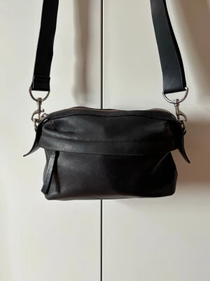 & Other Stories läderväska  - Läderväska i mjukt skinn. Möjligt att byta axelband. Axelbandet är slitet, delat sig och ena pluppen på haken är borta. 