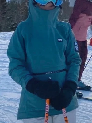 Skidjacka - Blå/grön skidjacka som man trär över som en hoodie. Varm, många fickor och går över hjälmen ❣️