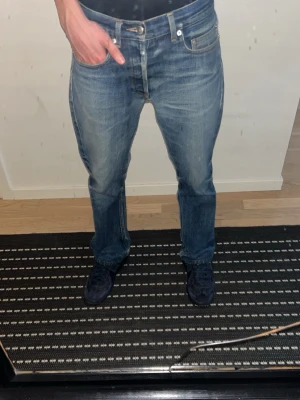 Blå raka jeans från A.P.C jeans - Säljer ett par klassiska blå selvedge jeans från A.P.C med rak passform och fem fickor. Jeansen har en snygg tvätt med lätt slitning och är tillverkade i denim. Perfekta för en avslappnad och stilren look.