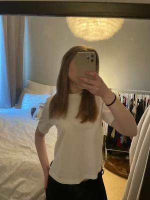 Vit kortärmad t-shirt - En enkel och stilren vit t-shirt med korta ärmar och rund hals. T-shirten har en rak passform och är gjord i mjukt bomullsmaterial, perfekt för en avslappnad look. Passar dig som gillar basic och clean stil.