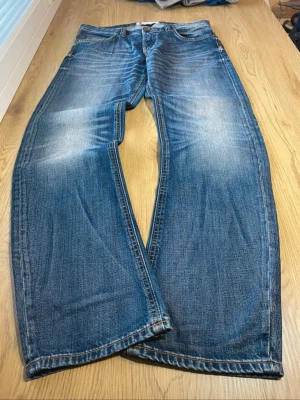 Dressmann straight fit jeans - Säljer ett par blåa straight fit jeans. Jeansen har klassisk femficksmodell, knappgylf och kontrastsömmar. Perfekta för en avslappnad och trendig stil. Storlek W33 L32