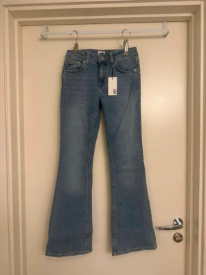 Bootcut jeans ljusblå XS - Ljusblå bootcut jeans i storlek XS med kort längd. Klassisk femficksdesign och snyggt utställda ben. Perfekt för dig som gillar en avslappnad och trendig look. Materialet är denim och jeansen har en låg midja.