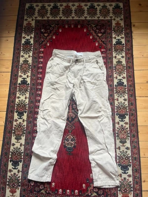 Beige linnebyxor  - Säljer ett par beige linnebyxor med avslappnad passform och knappar framtill. Byxorna har elastisk midja med dragsko och fickor både fram och bak.  