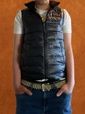 Svart dunväst från John Henric - Svart dunväst med quiltad design från John Henric och med krage. Västen har två sidofickor som stängs med magnet och stängs med en hel dragkedja framtill. Materialet är glansigt och lätt, perfekt för lager-på-lager eller en grich outfit till våren. Nypris 1200 mitt pris 700 skriv vid funderingar 😎😎😎🍾🍾🍾