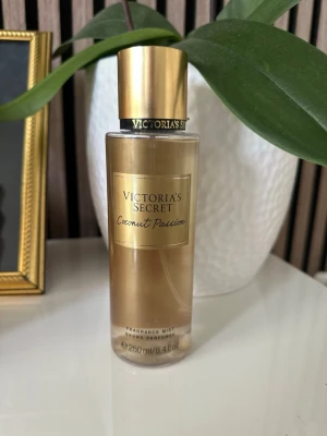 Victoria's Secret Coconut Passion mist - Fräsch body mist från Victoria's Secret i doften Coconut Passion. Flaskan är guld- och transparent med guldfärgat lock och elegant etikett. Innehåller 250 ml och har en tropisk, söt kokosdoft som känns lyxig och ungdomlig.