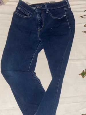 Mörkblå skinny jeans - Säljer ett par mörkblå Levi’s jeans med klassisk femficksdesign och smal passform. Jeansen har en enkel look utan slitningar och är tillverkade i stretchigt denimtyg för extra komfort. Perfekta till en avslappnad stil.