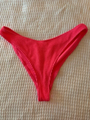 Rosa bikiniunderdel från H&M - Säljer en snygg rosa bikiniunderdel från H&M i storlek 42. Bikinin har en ribbad struktur och är tillverkad i ett stretchigt syntetmaterial som sitter bekvämt. Perfekt för lata dagar på stranden eller vid poolen!