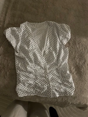 Vit blus med svarta prickar - Söt topp Säljer en söt prickig topp, 1 år gammal och oanvänd så kommer ej ihåg vart ifrån den är köpt. Stl L. Väldigt somrig och gullig. Noll defekter.
