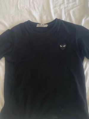 Comme des Garçons t-shirt - Svart t-shirt från Comme des Garçons Play med det ikoniska hjärtapplikationen med ögon på bröstet. Klassisk rund halsringning och korta ärmar. Perfekt för dig som gillar minimalistisk design och streetwear.