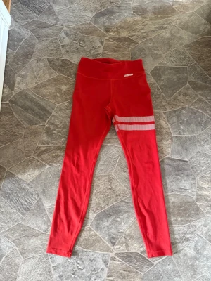 Röda Stronger Tights - Säljer röda träningstights från Stronger i storlek Small. Perfekt till dig som tränar mycket. Säljer för att de har blivit för små.