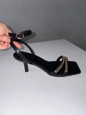 Sandaletter med guldkedja  - Helt nya! Aldrig använda.  Märke : Tiamo. Köpta på Scorett.  Storlek: 39 Klackhöjd: 8 cm