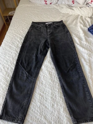 Svarta mom jeans från Koton - Säljer ett par svarta mom jeans från Koton med hög midja och raka ben. Jeansen har klassisk femficksdesign och bälteshällor. Perfekta för en avslappnad och trendig look. Materialet är denim i bomull.