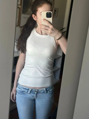 Vit ribbad linnetopp från Amisu - Säljer en vit ribbad linnetopp från Amisu. Toppen är ärmlös och har en tight passform med rund halsringning. Perfekt för att skapa en clean och enkel look. Materialet är mjukt och stretchigt, vilket gör den bekväm att bära.