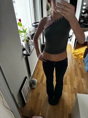 Mörkgrön oneshoulder croppad topp - Säljer en mörkgrön oneshoulder croppad topp. Snygg och tight passform som framhäver midjan, perfekt för dig som gillar trendiga och unika plagg. Materialet känns mjukt och stretchigt.