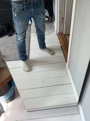 Blå replay skinny jeans med hål - Säljer ett par blå skinny jeans med slitningar och hål på låren och knäna. Jeansen har klassisk femficksmodell, gylf med knappar och en tvättad look som ger en cool streetkänsla. Perfekta för dig som gillar en trendig och avslappnad stil.