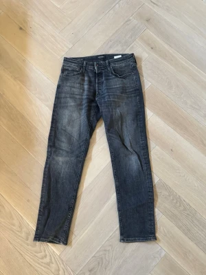 Mörkgrå Tapered/Mike Jeans - Snygga mörkgrå slim fit jeans med klassisk femficksdesign och lätt slitningar på framsidan. Jeansen har raka ben och är tillverkade i denim med en skön stretch. Perfekta för dig som gillar en stilren och avslappnad look.