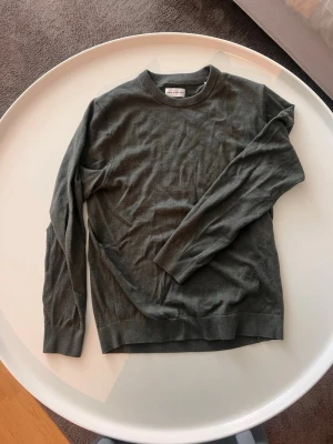 Grön stickad merino ull  tröja These Glory Days - En stilren grön  stickad merino ull  tröja från These Glory Days. Tröjan har rund halsringning, långa ärmar och ribbade muddar vid ärmslut och nederkant. 