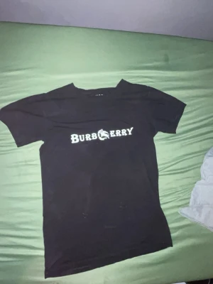 Svart Burberry t-shirt med tryck - Snygg svart t-shirt från Burberry med vitt tryck på bröstet där det står 'BURBERRY' och en cool drakdetalj i loggan. T-shirten har klassisk passform, rund hals och korta ärmar. Perfekt för dig som vill ha en statement tee i garderoben. Perfekt för sommaren 👌🏼