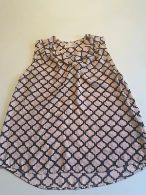 Mönstrad ärmlös topp från Emily Van Den Bergh - Säljer en snygg ärmlös topp från Emily Van Den Bergh med beige och svart grafiskt mönster. Toppen har en lös passform och ett mjukt, lätt tyg som känns skönt mot huden. Perfekt till sommaren och enkel att styla med jeans eller kjol.