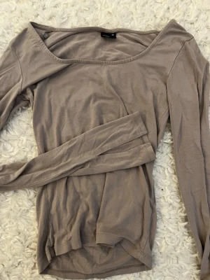 Beige långärmad topp Gina Tricot - Säljer en enkel och stilren beige långärmad topp från Gina Tricot. Toppen har en rundad halsringning och är tillverkad i ett mjukt material som känns skönt mot huden. Perfekt att matcha med jeans eller kjol för en clean look.