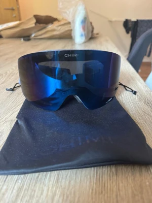 Chimi skidglasögon  - Blå/lila skidglasögon från Chimi. Glas för sol/ klara skiddagar. De är använda så de har lite ” fläckar” på glaset men det är inget som syns eller man märker när man har på sig de och åker med de i skidbacken. Köpt för 1500kr på chimis egna hemsida. Medföljer ett ljusgult glas för dimmiga/molniga skiddagar. Putsduk, tygpåse samt orginalbox till  glasögonen medföljer självklart också.