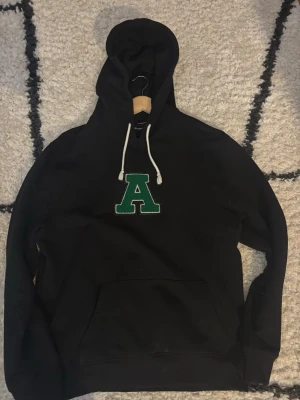 Axel Arigato, Svart Hoddie - Säljer min Arigato Hoddie som används fåtal gånger ,Klassisk känguruficka framtill och mjukt material, perfekt för en chill och avslappnad stil.