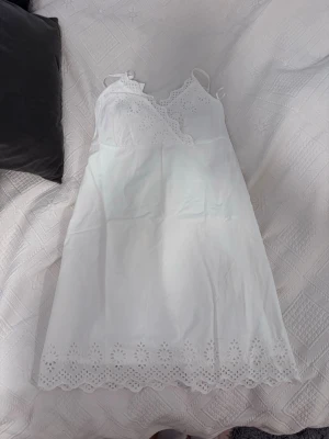 Vit sommarklänning med spetsdetaljer - Söt vit klänning med tunna axelband och vackra spetsdetaljer längs urringning och fåll. Klänningen är i storlek L men passar som M pågrund av små i storlek. Helt ny och oanvänd med lapp