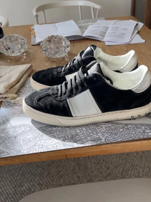 Svarta och vita sneakers från Valentino - Snygga sneakers från Valentino i svart mocka med vita detaljer och vit och tydlig logga på plösen. Pris är diskuterbart Perfekta för dig som vill ha en stilren och exklusiv look. Nån nit är dock av men kan skicka med extra nit.