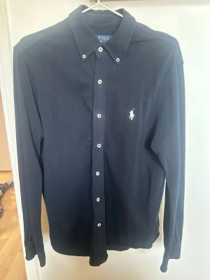 Mörkblå skjorta från Polo Ralph Lauren - Klassisk skön mörkblå raffe skjorta. Den är tillverkad i någon slags bomullsmix vilket gör den väldigt luftig och skön på sommaren. Hör av er vid frågor o funderingar